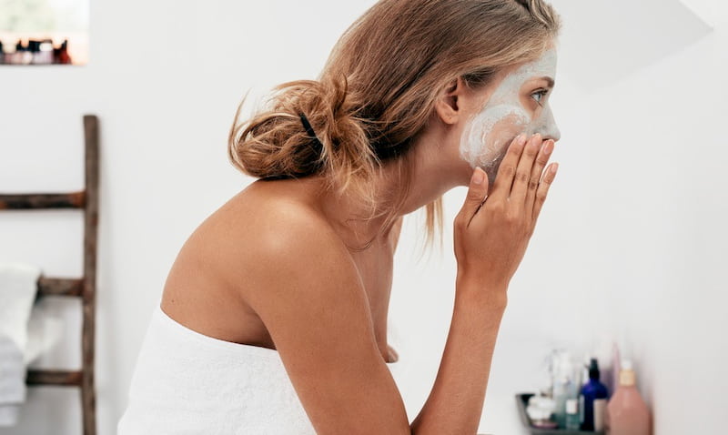 woman applying clay mask on her face