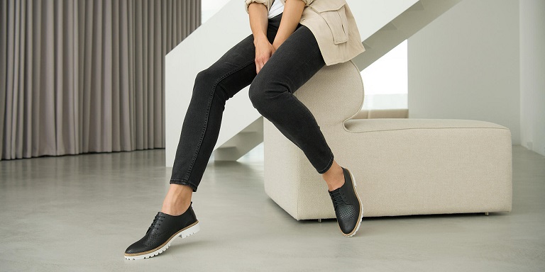 picture of a woman sitting in a hallway wearing stylish outfit and black ECCO shoes