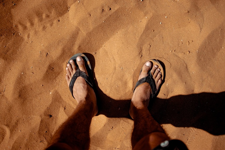 picture of persons feet in slides on sand