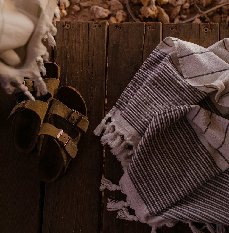 picture of a slip on sandals on a wooden panel beside textile