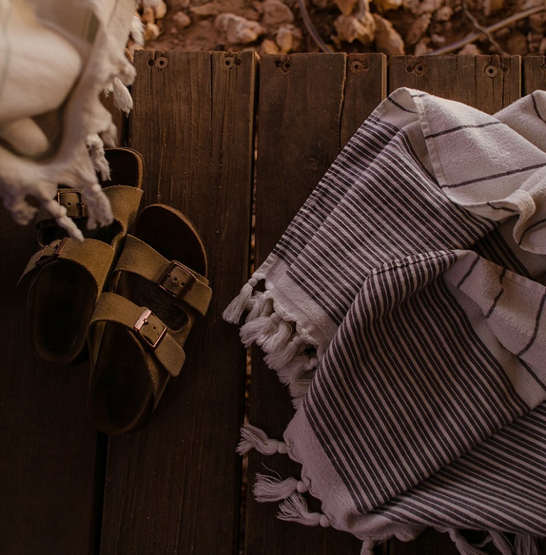 picture of a slip on sandals on a wooden panel beside textile 