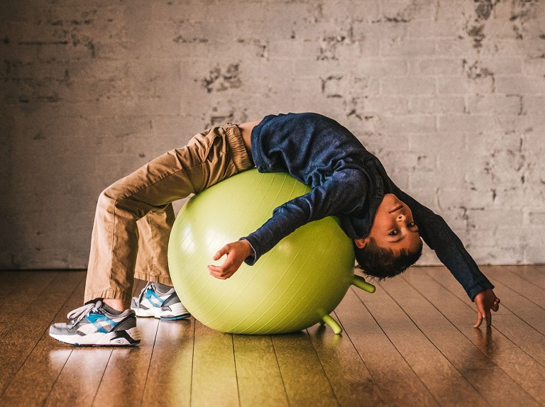 kid streching on sensory ball