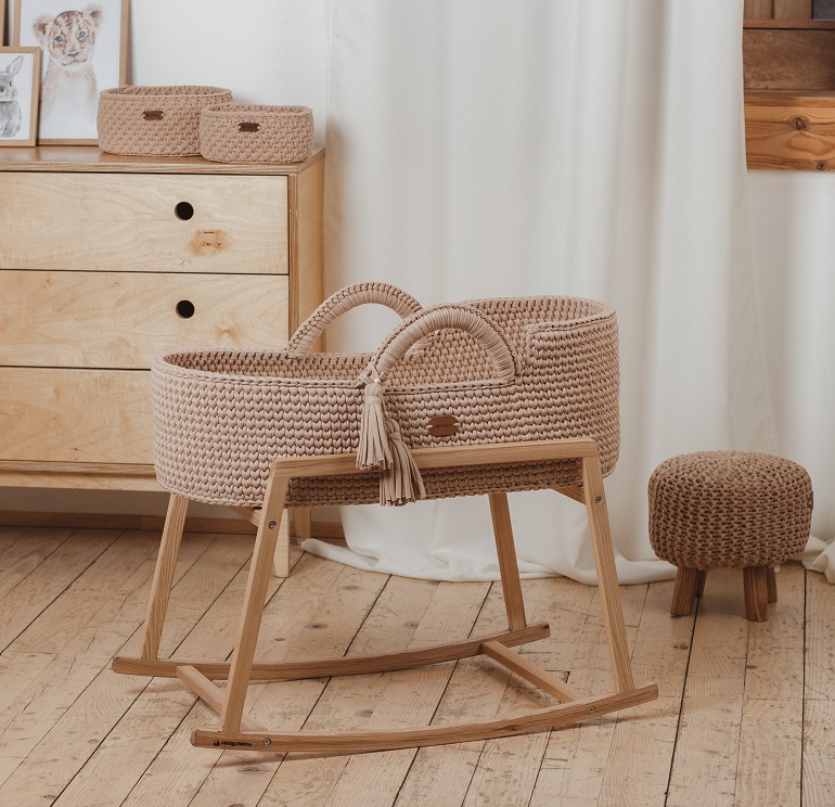 picture of a baby Moses basket on a wooden floor beside a wooden dresser  