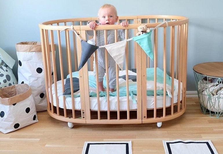 picture of a baby in a baby cot  with wheels 