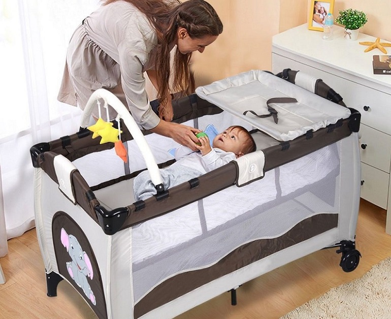 picture of a woman standing beside a baby in a crib in front a dresser 