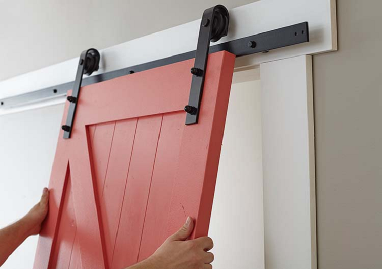 hands holding up a red sliding barn door