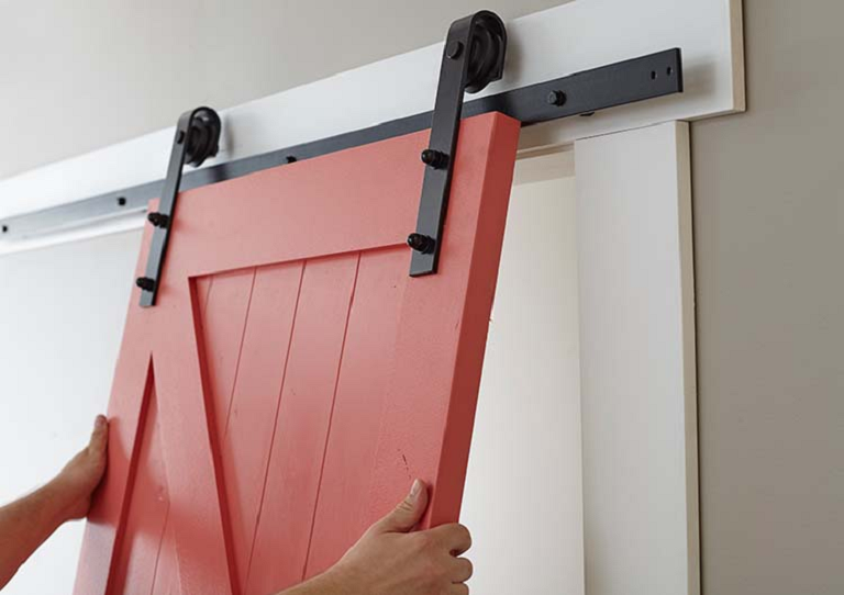 hands holding up a red sliding barn door 