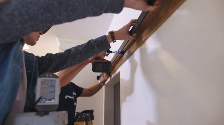 people installing sliding door hardware on wall 