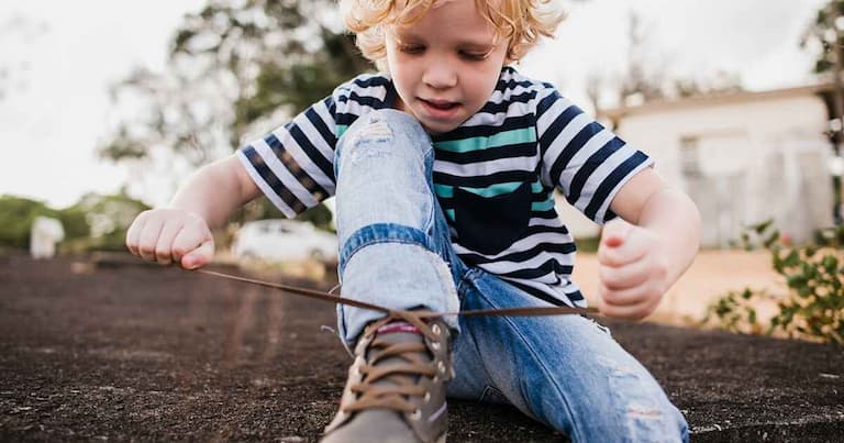 little kid tying laces on his sneakers