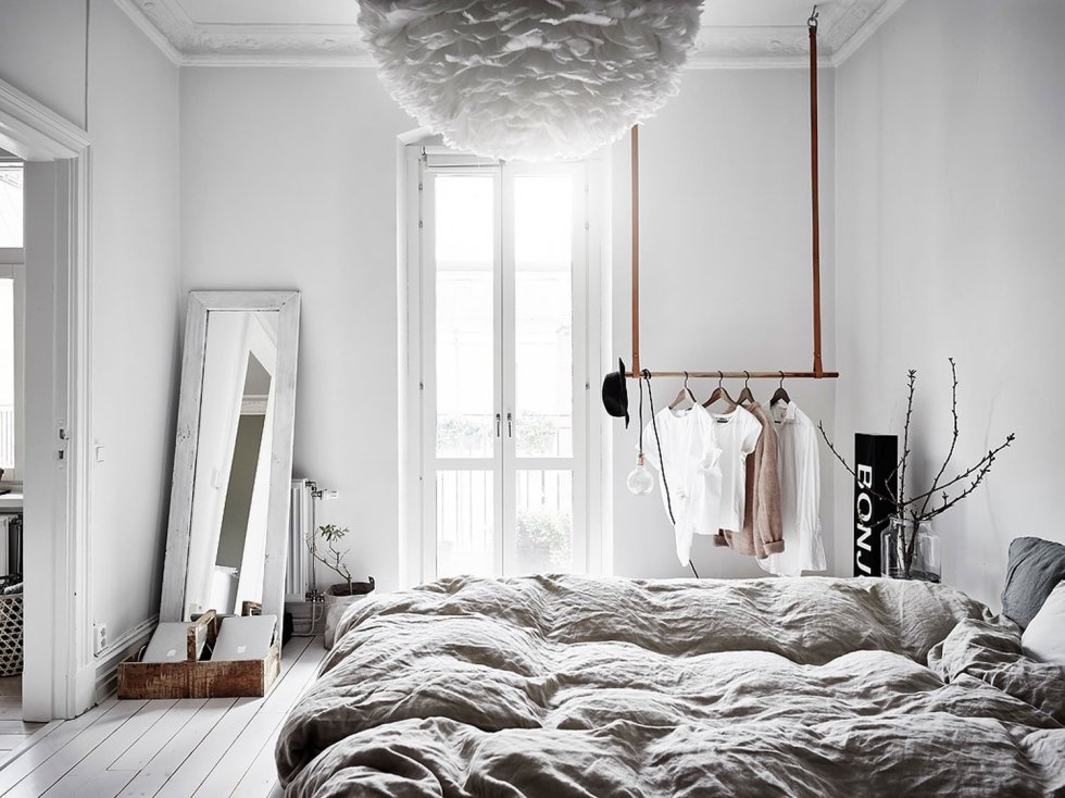 Scandinavian Bedroom design with a mirror in a frame railing for clothes, a paper ruffle lamp and grey bedding