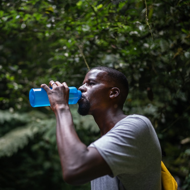 black man drinking water in nature